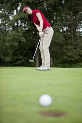 Eine Golferin beim Putten, Golfball am Rand des Lochs - FSIF02924