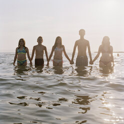 Five friends holding hands in a row while wading in the sea - FSIF02940