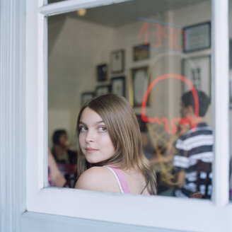 Ein junges Mädchen schaut durch das Fenster eines Cafés - FSIF02946