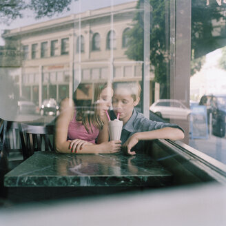 Ein junges Teenager-Paar, das sich in einem Diner einen Milchshake gönnt, durch ein Fenster gesehen - FSIF02950
