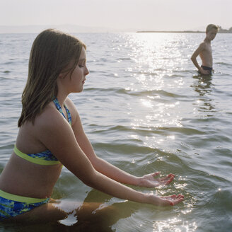 Ein junges Mädchen schöpft Wasser, während es im Meer watet - FSIF02954