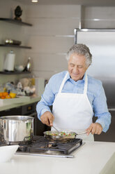 A senior man cooking vegetables in a saute pan - FSIF02988