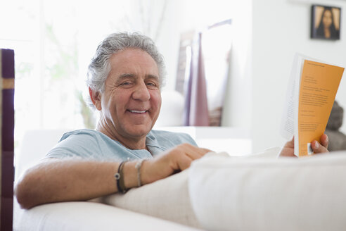 A cheerful senior man reading a book at home - FSIF02990