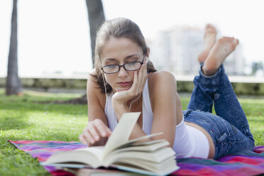 Mädchen liegt lesend im Park - FSIF02993