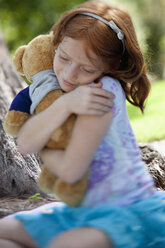 Mädchen, das einen Teddybär umarmt - FSIF02994