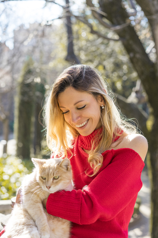 Happy young woman holding a cat in a garden stock photo