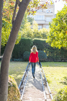 Junge Frau geht auf einem Weg in einem Garten - AFVF00186