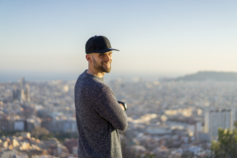 Spain, Barcelona, smiling young man standing on a hill overlooking the city stock photo