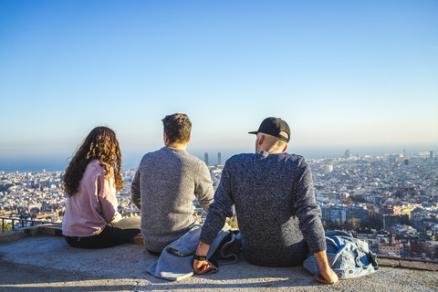 Spain, Barcelona, three friends sitting on a wall overlooking the city stock photo