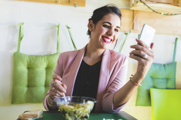 Junge Geschäftsfrau, die gesund zu Mittag isst und ein Mobiltelefon benutzt - WPEF00129