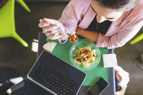 Young businesswoman having healthy lunch and using laptop stock photo