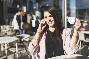 Lächelnde junge Geschäftsfrau am Handy in einem Straßencafé - WPEF00140