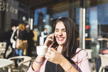 Lachende junge Geschäftsfrau am Handy in einem Straßencafé - WPEF00141