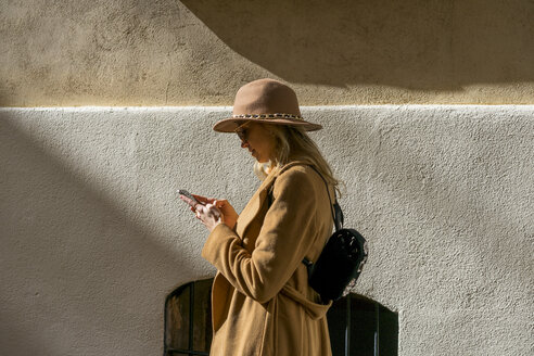 Modische junge Frau in einem Gebäude, die ein Mobiltelefon benutzt - AFVF00235