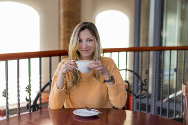 Portrait of smiling young woman in a cafe enjoying a coffee - AFVF00243