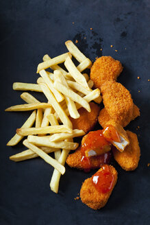 Chicken Nuggets mit süßer Chilisauce und Pommes frites auf dunklem Grund - CSF28940