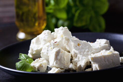 Feta, herbes and basil leaves on black plate, close-up - CSF28986