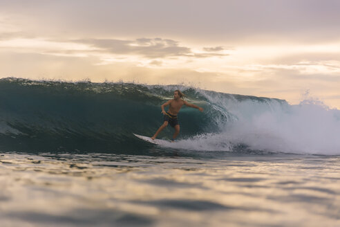 Indonesien, Sumatra, Surfer auf einer Welle bei Sonnenuntergang - KNTF00977