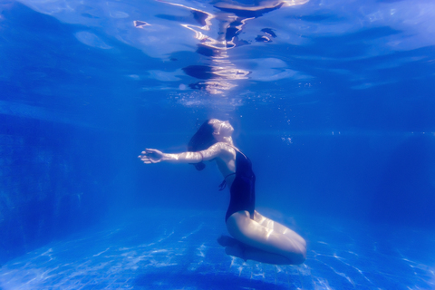 Junge Frau unter Wasser in einem Schwimmbad, lizenzfreies Stockfoto