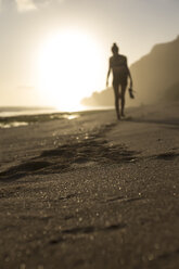 Indonesia, Bali, woman walking on the beach at sunset - KNTF00995
