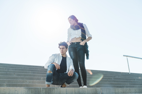 Porträt eines stilvollen jungen Paares auf einer Treppe im Freien, lizenzfreies Stockfoto