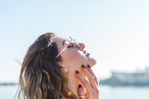 Portrait of young woman wearing sunglasses under blue sky stock photo