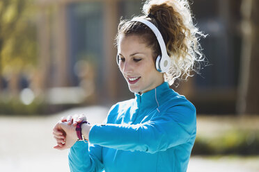 Sportive young woman with headphones checking the time - JSRF00009