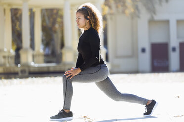 Young woman with earphones stretching - JSRF00013