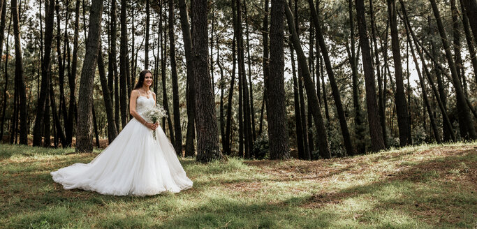 Lächelnde Braut mit Blumenstrauß im Wald - DAPF00888