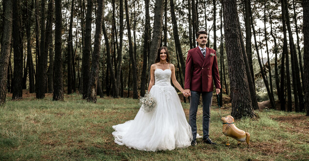Glückliche Braut und Bräutigam stehen im Wald mit lustigen Hund-förmigen Ballon - DAPF00890