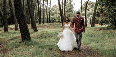 Happy bride and groom walking in forest stock photo