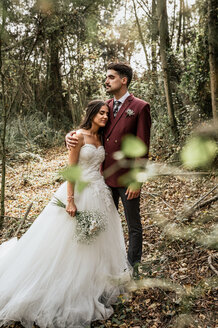 Bräutigam umarmt die Braut mit geschlossenen Augen im Wald - DAPF00902