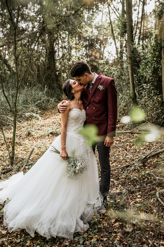 Bride and groom standing in forest kissing stock photo