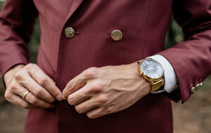 Nahaufnahme eines Mannes im Anzug mit goldener Uhr, der seine Jacke zuknöpft - DAPF00907