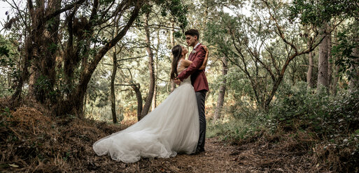 Braut und Bräutigam stehen sich umarmend im Wald - DAPF00909