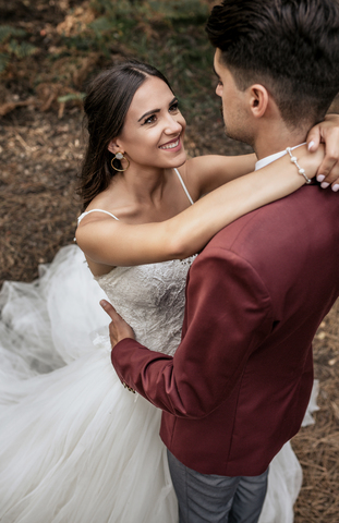 Portrait of beautiful bride embracing and looking to man outdoors stock photo