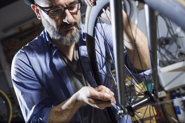 Man working on bicycle in workshop - JSRF00020