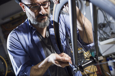 Mann arbeitet in einer Werkstatt an einem Fahrrad - JSRF00020