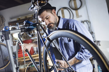 Mann arbeitet in einer Werkstatt an einem Fahrrad - JSRF00022