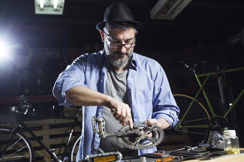 Mann arbeitet in einer Werkstatt an einem Fahrrad, lizenzfreies Stockfoto