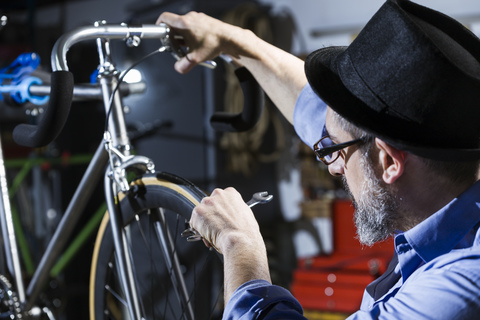 Mann arbeitet in einer Werkstatt an einem Fahrrad, lizenzfreies Stockfoto