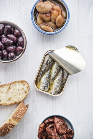 Tin can of sardines in oil, bowls of pickled vegetables and slices of bread stock photo