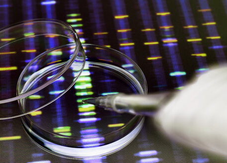 Sample of DNA being pipetted into a petri dish over genetic results - ABRF00114