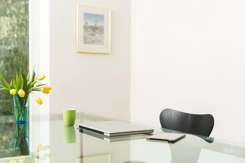 Laptop und Tablet auf einem Glastisch im Wohnzimmer, lizenzfreies Stockfoto