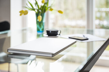 Laptop on glass table in living room - JHAF00014