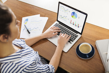 Young woman working on charts on her laptop at home - JHAF00016