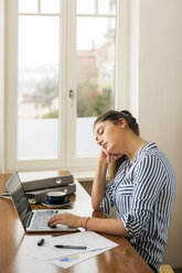 Junge Frau, die zu Hause vor ihrem Laptop schläft - JHAF00018