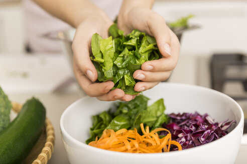 Hände legen frischen Salat in eine Schüssel mit verschiedenen Gemüsesorten - JHAF00023