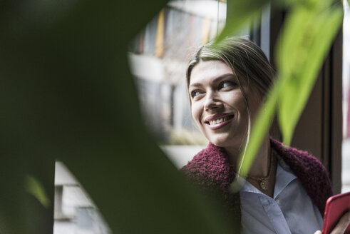 Lächelnde junge Frau am Fenster - UUF12832