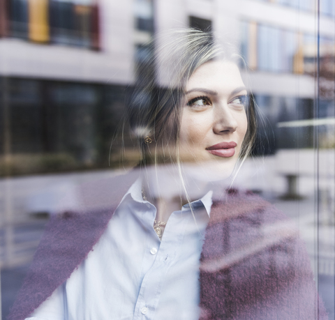 Smiling young woman looking out of window stock photo